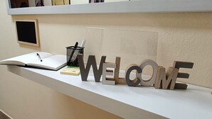 Un mostrador de recepción con un cartel que dice 'WELCOME', un libro abierto y un bolígrafo encima.