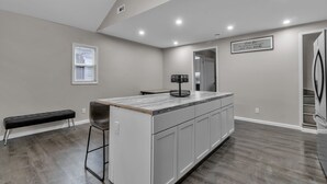 A modern kitchen with a central island, a bench, and a dining area. - The Davey Retreat (Buffalo)