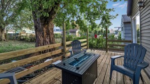 A wooden deck with a table and two chairs, surrounded by a wooden fence and a large tree. - The Davey Retreat (Buffalo)