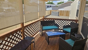 Eine Terrasse im Freien mit Korbmöbeln, einem Holzdeck und einem überdachten Bereich mit Moskitonetz.