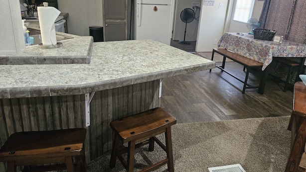 Eine Küche mit Granit Arbeitsplatten, einem Kühlschrank, einem Ventilator und einem Essbereich mit Tisch und Bank.