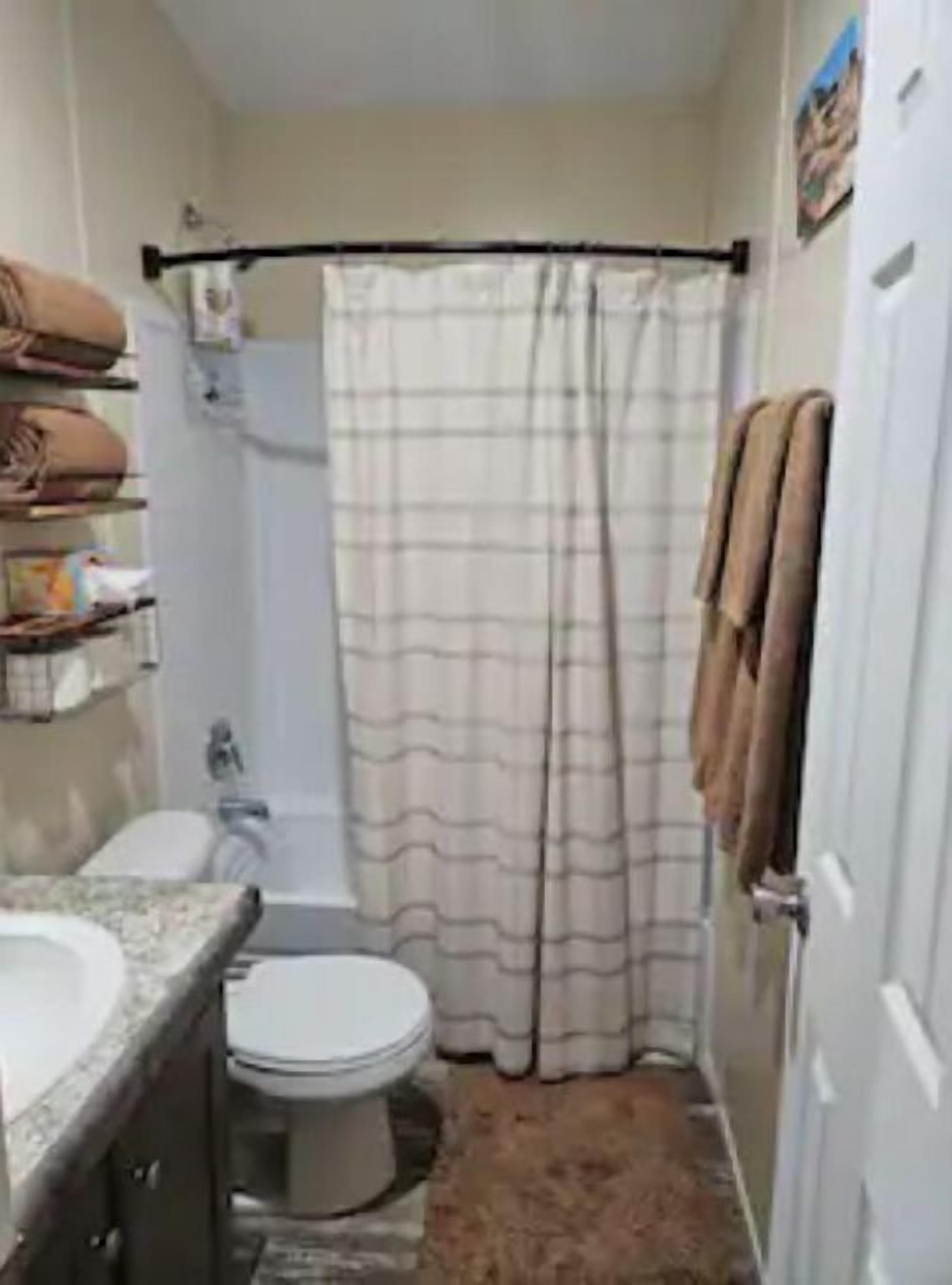 Un baño pequeño con inodoro, lavabo, cortina de ducha y toallero.