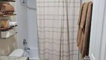 Un baño pequeño con inodoro, lavabo, cortina de ducha y toallero.