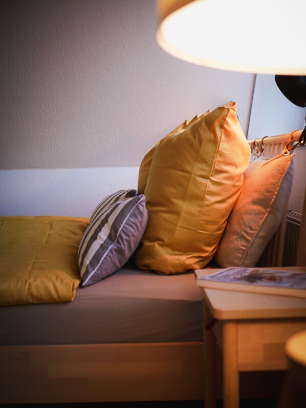 Ein Bett mit mehreren Kissen, einem Nachttisch und einer Lampe.