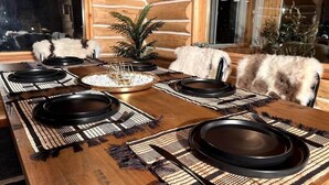 A dining table set with black plates, a central decorative piece, and a plant. - Family Cabin + Games Barn | Hot Tub | Theatre (Columbia-Shuswap)