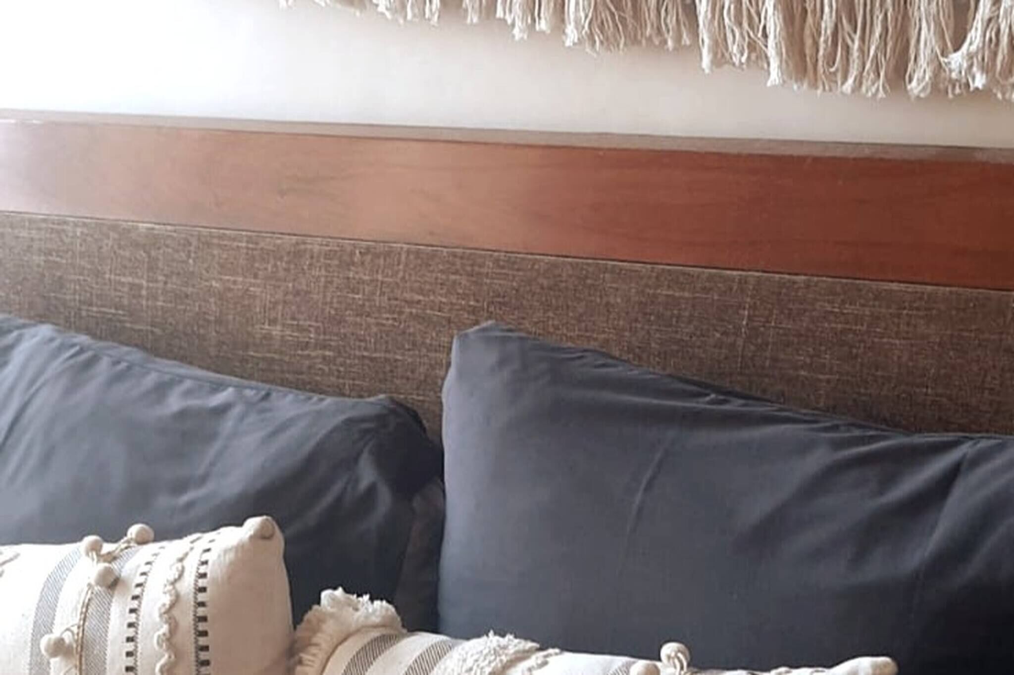 Parte de um quarto com cabeceira de madeira e dois sofás escuros.