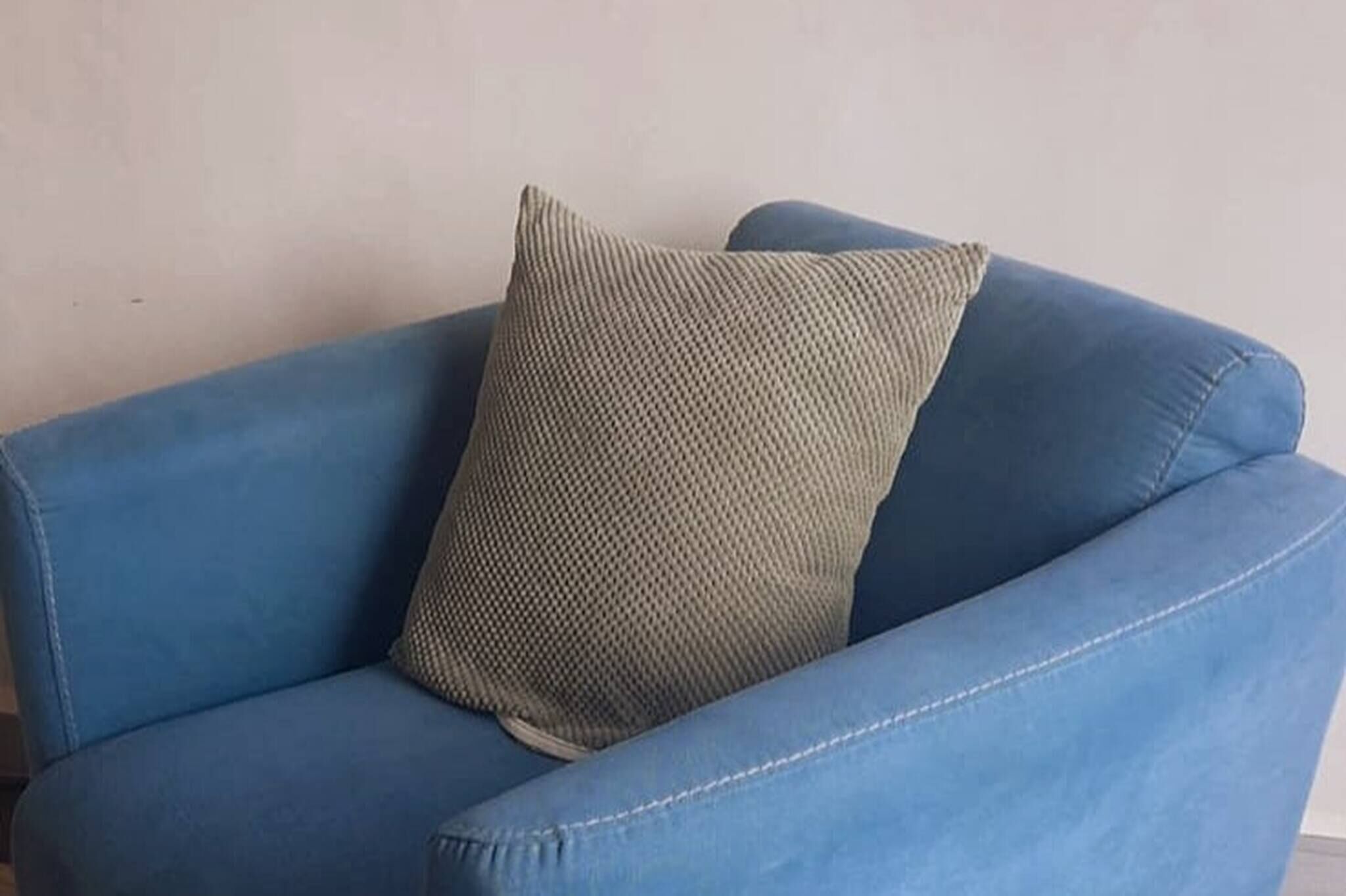 A blue sofa with a textured pillow.
