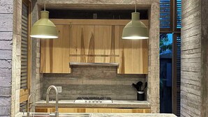 Een moderne keuken met houten kastjes, een groot eiland met barkrukken en hanglampen.