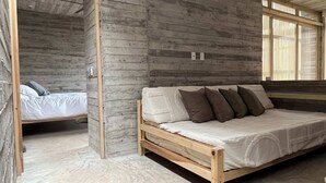 Una habitación con una cama de madera, un banco de madera y una ventana con persianas.