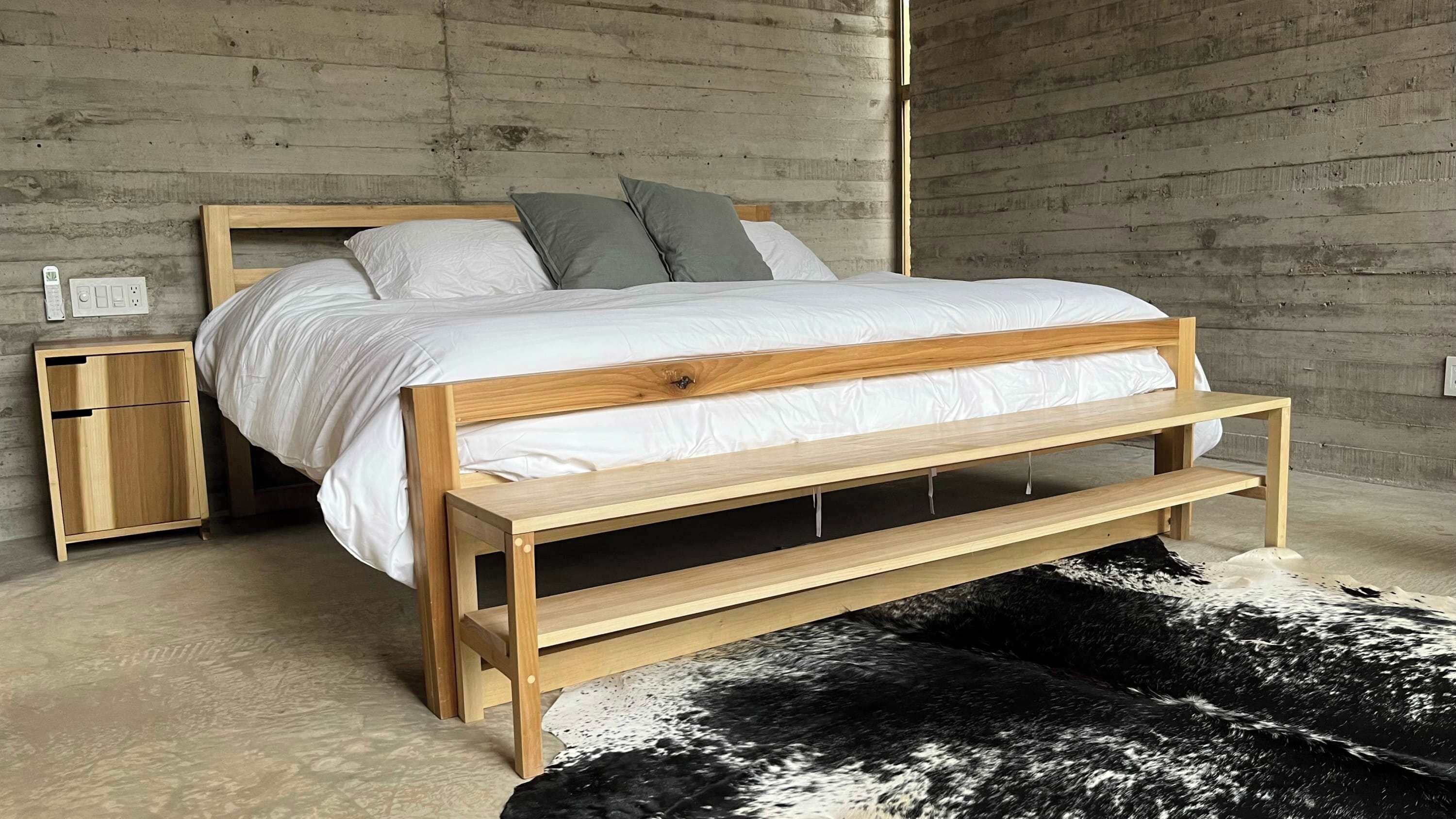 A bed with a wooden frame, a nightstand, and a black and white rug.