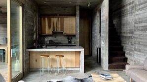 Eine moderne Küche mit Holzausstattung, einer zentralen Kochinsel mit Barhocker und einer Treppe zu einer weiteren Ebene.