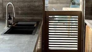 Eine moderne Küche mit integriertem Spülbecken, Holzschränken und einem Fenster mit Jalousien.