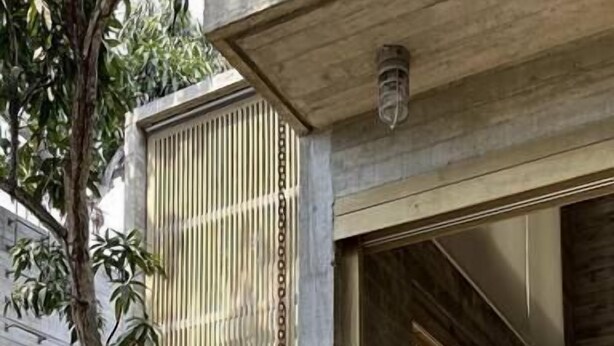 Ein modernes Haus mit einer Holzterrasse, einem Hängesessel und einem großen Baum.