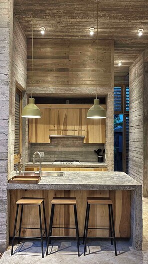 Une cuisine moderne avec des meubles en bois, un grand îlot central doté de tabourets et un éclairage suspendu.
