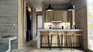 Una cocina moderna con armarios de madera, una isla central con taburetes e iluminación colgante.