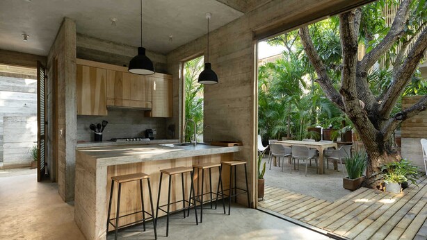 Una cocina moderna con una isla grande, taburetes de bar e iluminación colgante.