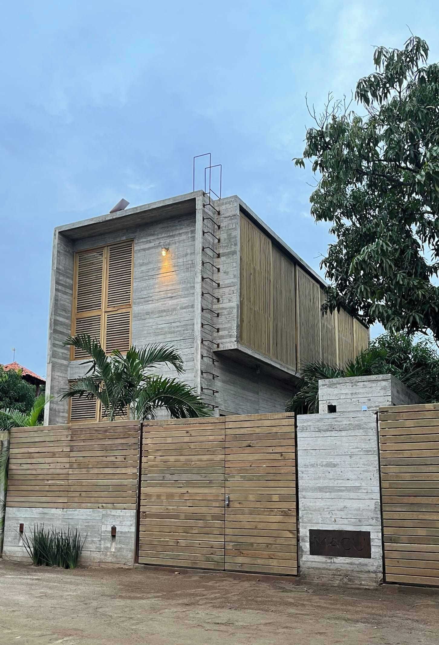 A modern building with a concrete facade, wooden shutters, and a gated entrance.