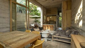A modern, open-plan living space with a wooden interior, a dining area, and a kitchen. - Casa Macu - Surf Oasis: Full House w/ Pools Steps From Waves (Playa La Saladita)