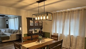 A dining area with a wooden table, chairs, and a hanging light fixture. - Fantastic Master’s Rental- 1 mile away! (Augusta)
