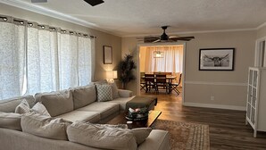 A living room with a sofa, coffee table, and a dining area with a table and chairs. - Fantastic Master’s Rental- 1 mile away! (Augusta)