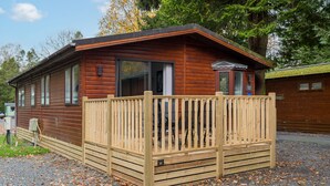 A wooden cabin with a wooden deck, large windows, and a door. - Firgarth Lodge  - sleeps 6 guests  in 3 bedrooms (Windermere)