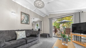 A modern living room with a grey sofa, a wooden coffee table, and a TV on a wooden stand. - Firgarth Lodge  - sleeps 6 guests  in 3 bedrooms (Windermere)
