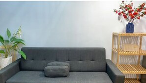 Relax in this stylish living room with a comfortable sofa, matching ottoman, and a beautiful potted plant.