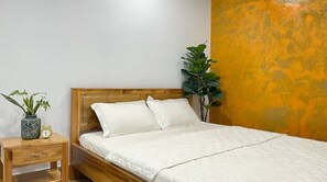 Cozy retreat with a single bed, nightstand, and two potted plants.