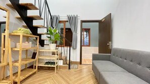 Relax in this stylish living room with a sofa, staircase, and potted plant.