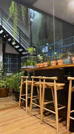 Enjoy casual dining and socializing in this inviting space with a bar area, floor-to-ceiling windows, and lush greenery.