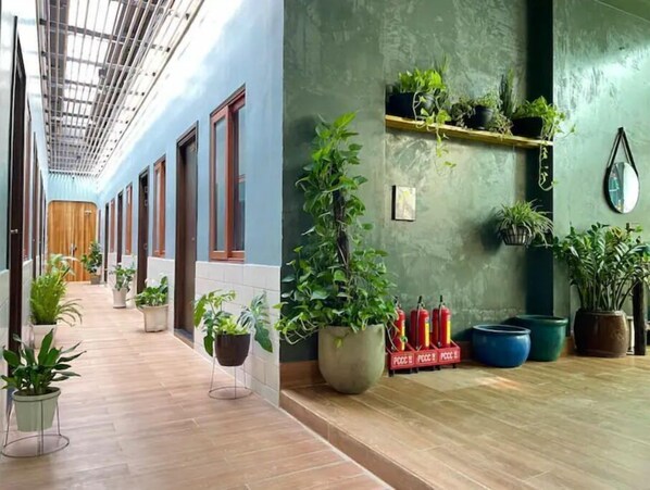 Stylish hallway with potted plants and fire extinguishers, set against a clean and bright backdrop.