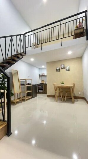 Cozy dining area with a table, chairs, and a potted plant, plus a staircase leading to an upper level.
