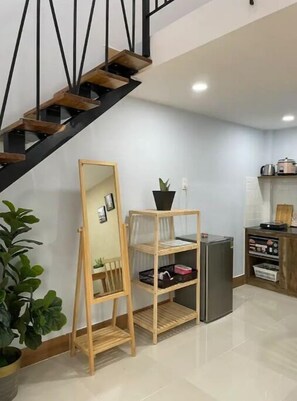Staircase and mirror stand in a contemporary living area with a potted plant.