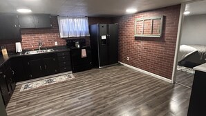 A compact kitchen with dark cabinets, a black refrigerator, and a wooden floor.