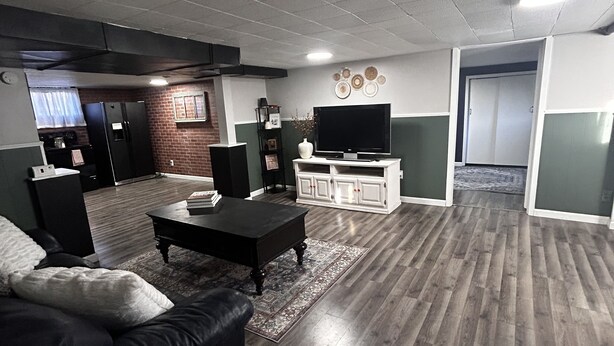 A living room with a black leather sofa, a coffee table, a flat-screen TV, and a white cabinet.