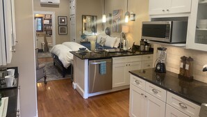 Una cocina compacta con una isla central, electrodomésticos de acero inoxidable y muebles de color blanco.