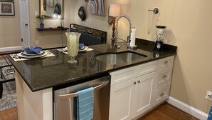 Una cocina moderna con encimera de granito, electrodomésticos de acero inoxidable y armarios blancos.