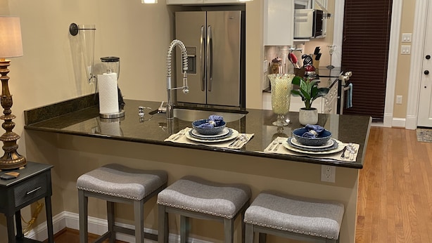 Una cocina moderna con una isla central, electrodomésticos de acero inoxidable y taburetes de bar.