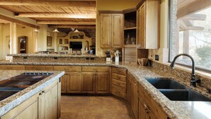 A spacious kitchen with granite countertops, wooden cabinets, and a large island with a stovetop.