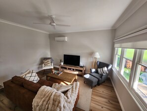A living room with a sofa, coffee table, TV, and a ceiling fan.