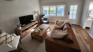 Ein Wohnzimmer mit Fernseher, Sofa, Couchtisch und Deckenventilator.