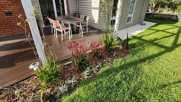 Ein Haus mit Terrasse, Sitzgelegenheit im Freien und einem Garten.
