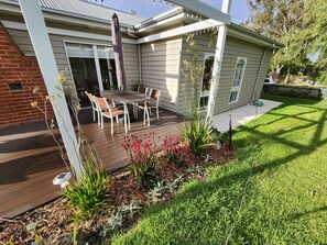 A house with a deck, outdoor seating, and a garden.