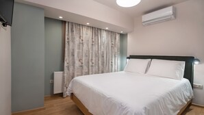 A bedroom with a bed, a radiator, curtains, and an air conditioning unit.