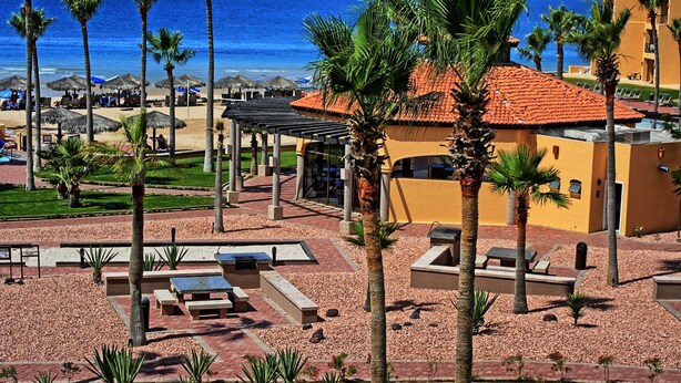 Ein Resort mit Poolbereich, Palmen und Meerblick.