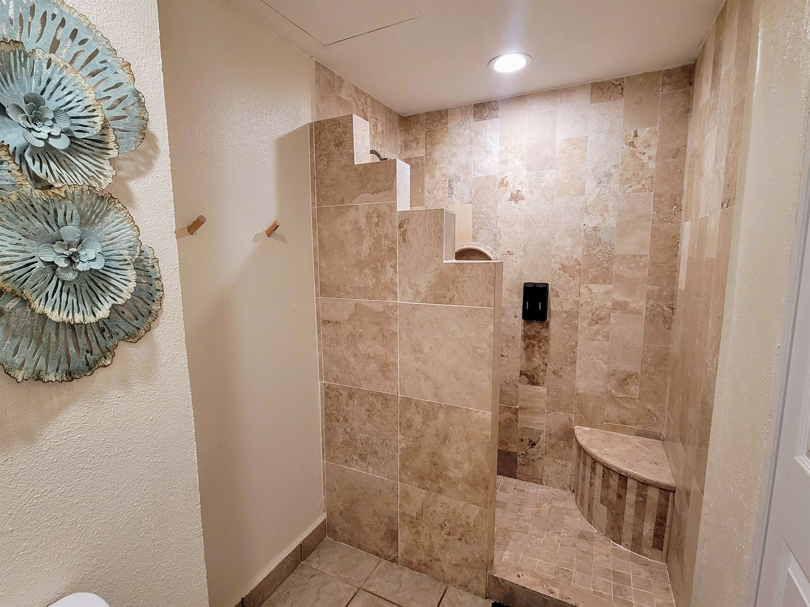 Un bagno con doccia, pareti piastrellate e un elemento decorativo a parete.