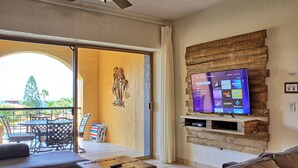 Sala de estar con televisor montado en una pared de madera, mesa de billar y mobiliario para exteriores.