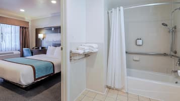 A hotel room with a bed, a shower, and a view of the cityscape.