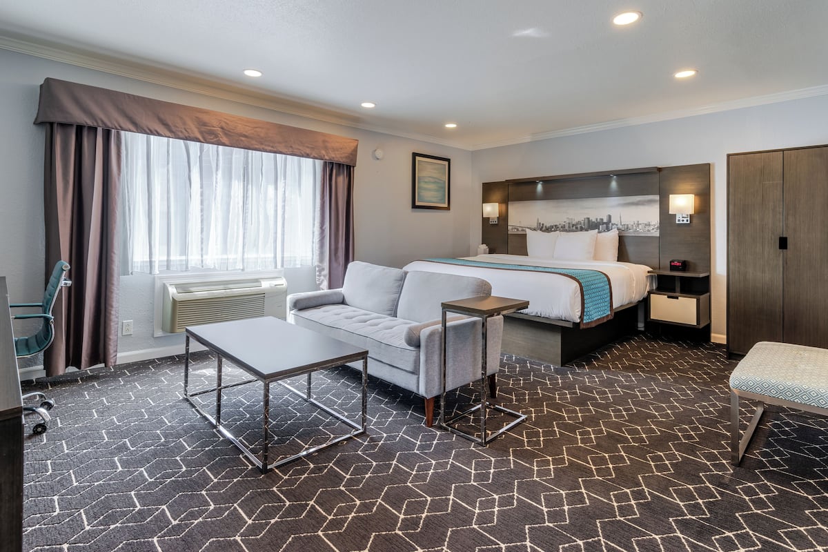 Une chambre d’hôtel avec un lit, un canapé, une petite table, une chaise et un bureau.