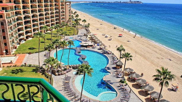 A resort with a swimming pool, beach, and ocean view.